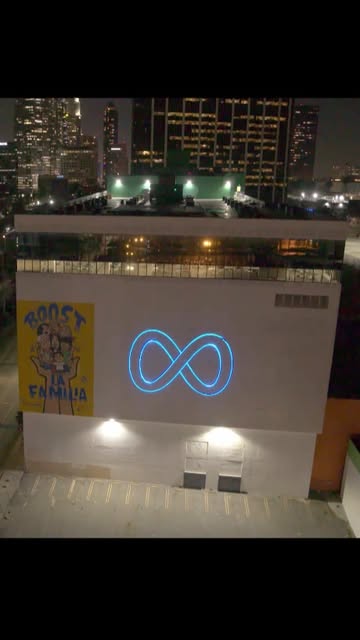 Concept demo: the Meta infinity logo projected in blue light on a building facade below a city skyline at night.